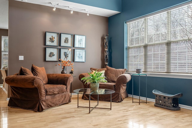 sitting room with track lighting, baseboards, and wood finished floors