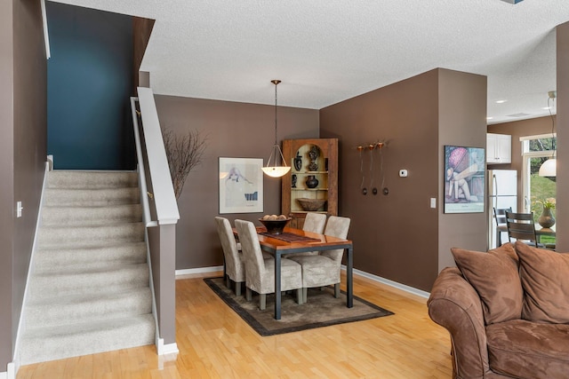 dining space featuring light wood-style floors, stairway, and baseboards