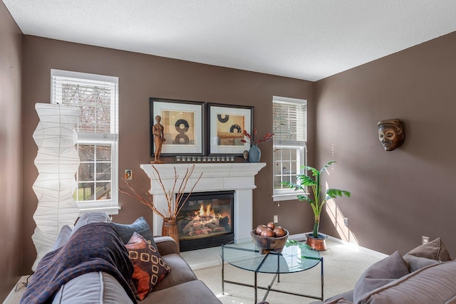 living area featuring a glass covered fireplace and a textured ceiling