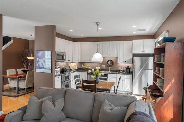 kitchen featuring dark countertops, appliances with stainless steel finishes, open floor plan, and white cabinetry