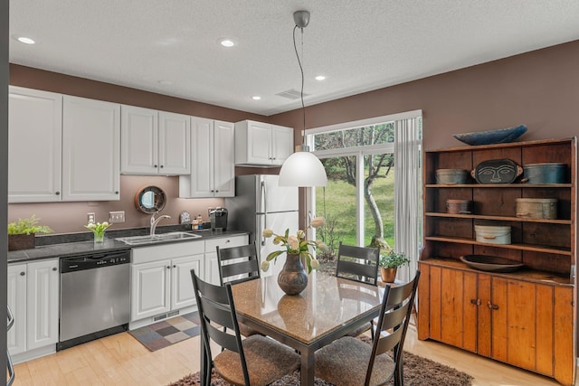 kitchen with white cabinets, dark countertops, appliances with stainless steel finishes, and a sink