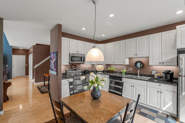 kitchen with dark countertops, appliances with stainless steel finishes, a sink, and white cabinetry