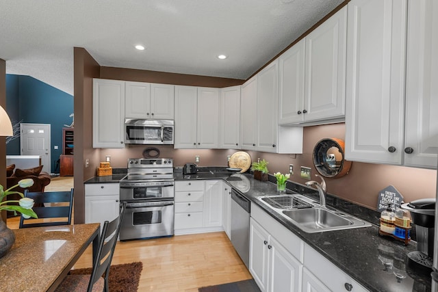 kitchen with light wood-type flooring, a sink, white cabinetry, and appliances with stainless steel finishes