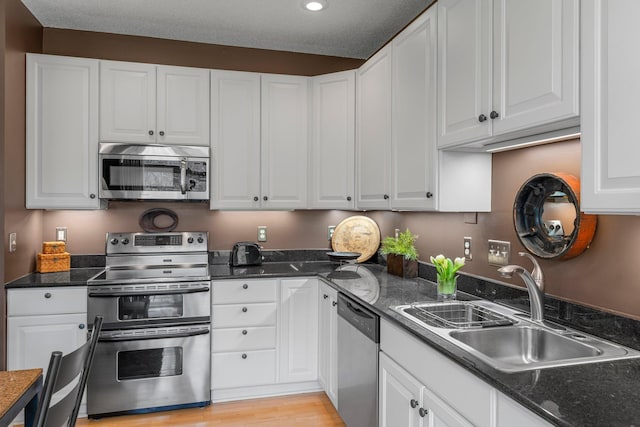 kitchen with recessed lighting, stainless steel appliances, a sink, and white cabinetry