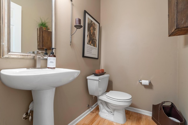 half bath featuring toilet, wood finished floors, and baseboards
