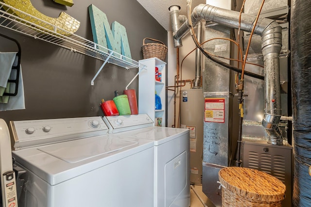 clothes washing area featuring washing machine and clothes dryer, laundry area, and gas water heater