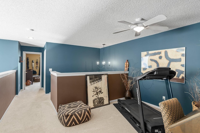 exercise area featuring carpet, a ceiling fan, baseboards, and a textured ceiling