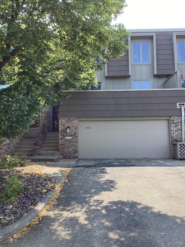 view of front of house with brick siding, aphalt driveway, stairs, and a garage