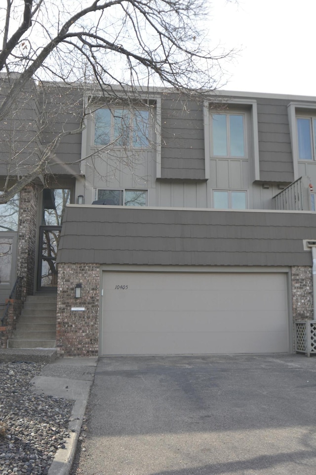 view of front facade featuring brick siding, an attached garage, and driveway
