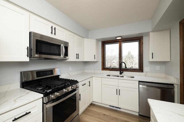 kitchen with white cabinets, light stone counters, visible vents, a sink, and appliances with stainless steel finishes