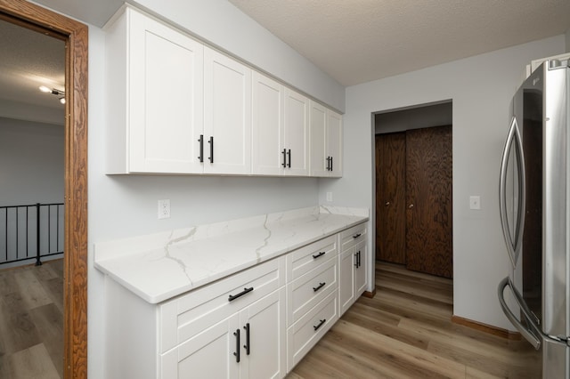 kitchen featuring freestanding refrigerator, light wood-style flooring, and white cabinetry