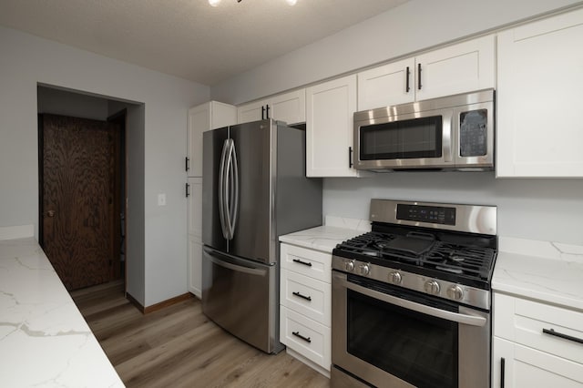 kitchen featuring white cabinets, light stone countertops, baseboards, and stainless steel appliances