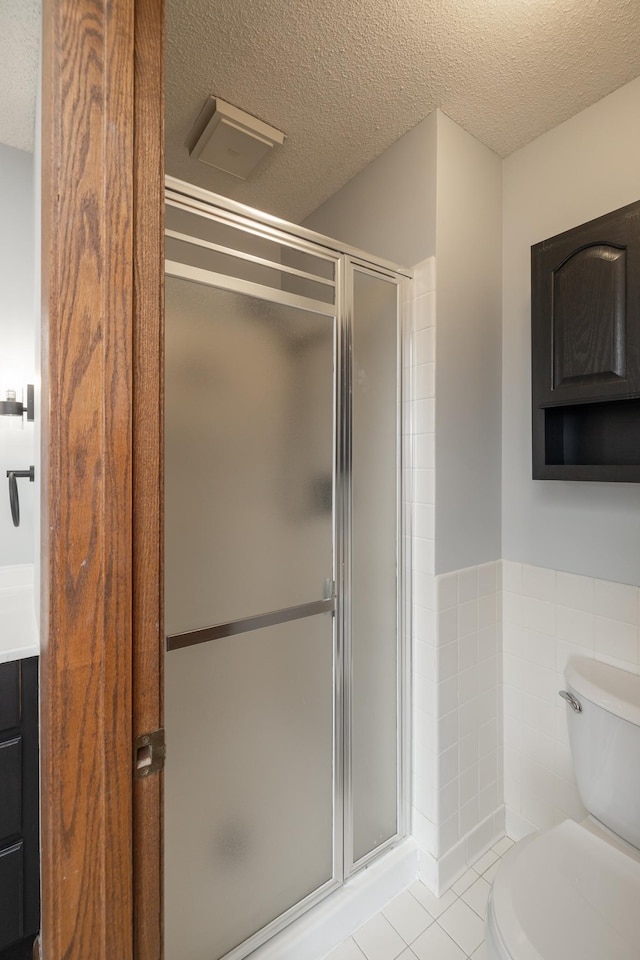 bathroom featuring tile patterned flooring, a shower stall, and toilet