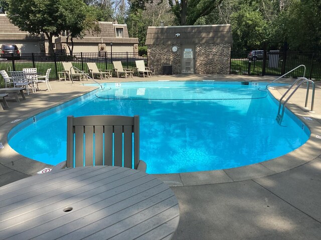 community pool with a patio and fence