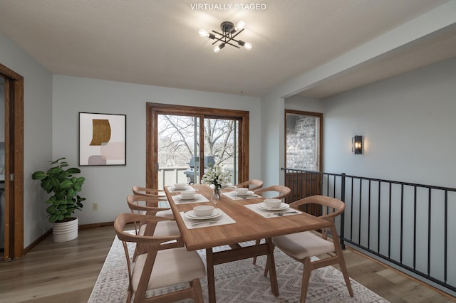 dining room with light wood-style flooring, baseboards, and an inviting chandelier
