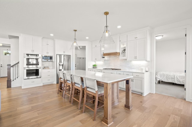 4429 Arbor Dr, Woodbury, MN 55129 - kitchen featuring appliances with stainless steel finishes, light wood-type flooring, decorative backsplash, a kitchen bar, and light countertops