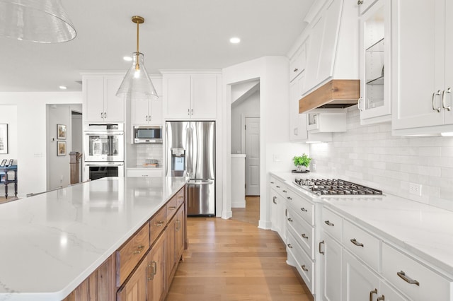 4429 Arbor Dr, Woodbury, MN 55129 - kitchen featuring stainless steel appliances, a center island, light wood-style flooring, white cabinets, and decorative backsplash