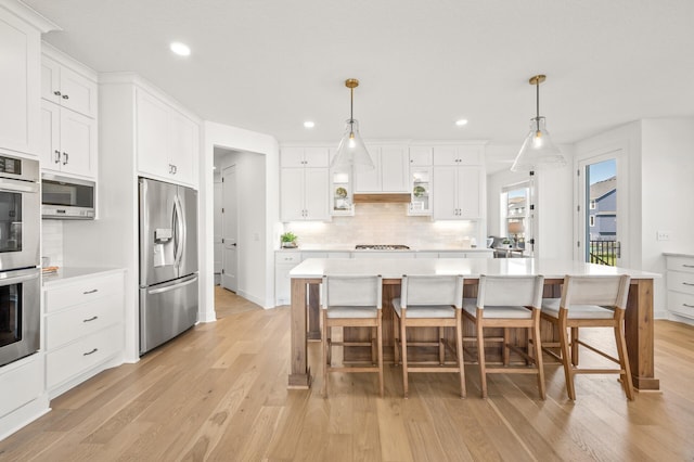 4429 Arbor Dr, Woodbury, MN 55129 - kitchen featuring stainless steel appliances, light wood-style flooring, tasteful backsplash, light countertops, and recessed lighting