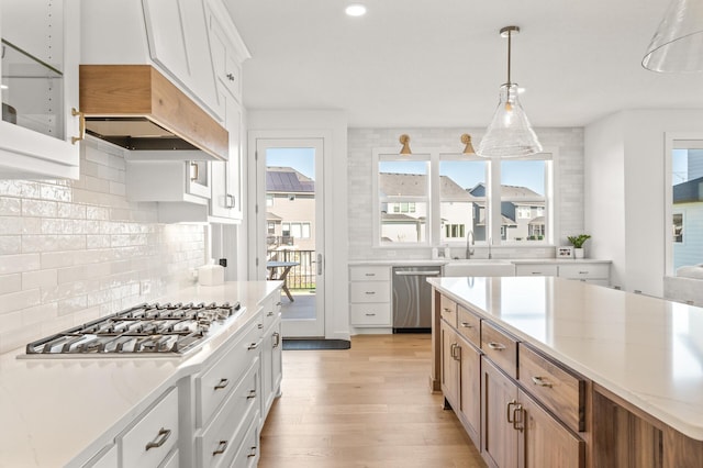 4429 Arbor Dr, Woodbury, MN 55129 - kitchen featuring stainless steel appliances, a sink, light wood-style flooring, backsplash, and hanging light fixtures