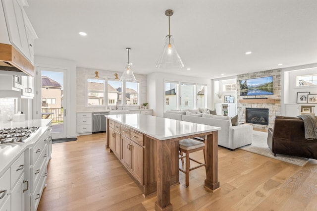 4429 Arbor Dr, Woodbury, MN 55129 - kitchen with a sink, appliances with stainless steel finishes, light wood-style floors, a stone fireplace, and light countertops