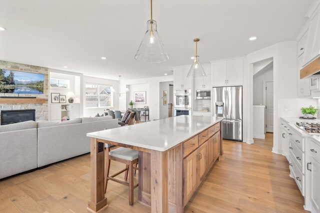 4429 Arbor Dr, Woodbury, MN 55129 - kitchen featuring stainless steel appliances, open floor plan, light wood-style flooring, white cabinetry, and recessed lighting