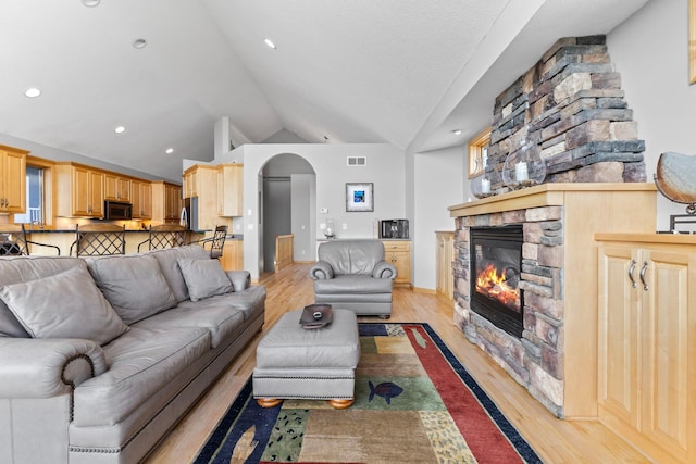 4101 Highwood Rd, Orono, MN 55364 - living area featuring visible vents, arched walkways, a fireplace, vaulted ceiling, and light wood-type flooring