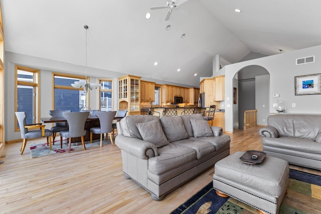 4101 Highwood Rd, Orono, MN 55364 - living area with visible vents, light wood-style floors, high vaulted ceiling, arched walkways, and ceiling fan with notable chandelier