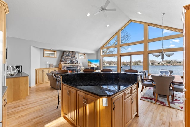 4101 Highwood Rd, Orono, MN 55364 - kitchen featuring a kitchen island, a fireplace, high vaulted ceiling, light wood finished floors, and ceiling fan with notable chandelier