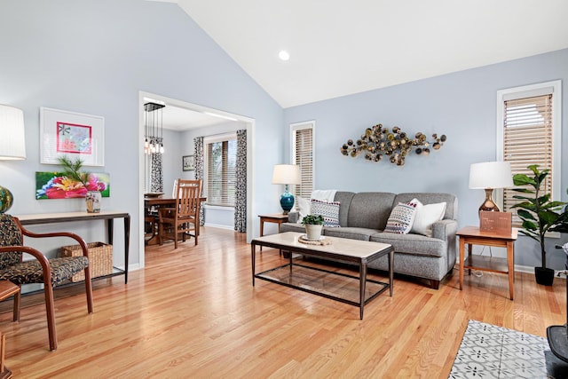 living area featuring baseboards, plenty of natural light, light wood-style flooring, and high vaulted ceiling