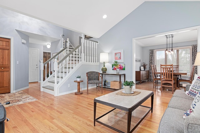 living room with stairway, baseboards, light wood-type flooring, and a chandelier