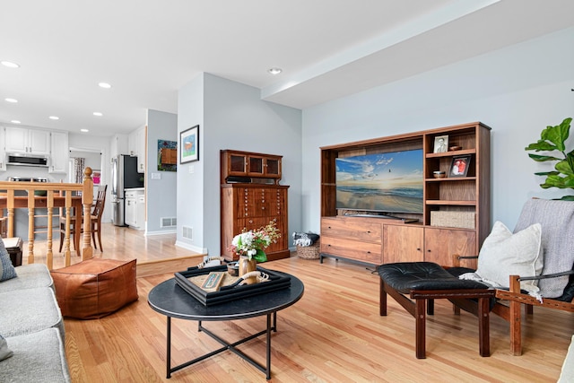 living room featuring baseboards, recessed lighting, light wood-style flooring, and visible vents