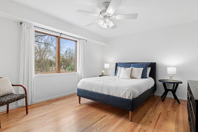 bedroom featuring baseboards, a ceiling fan, and light wood-style flooring