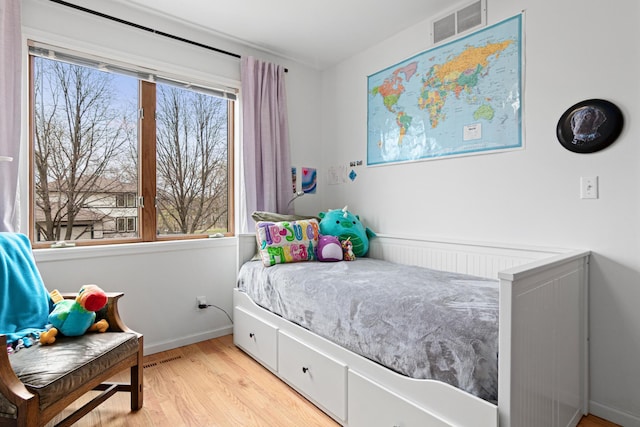 bedroom featuring radiator heating unit, baseboards, light wood-type flooring, and visible vents