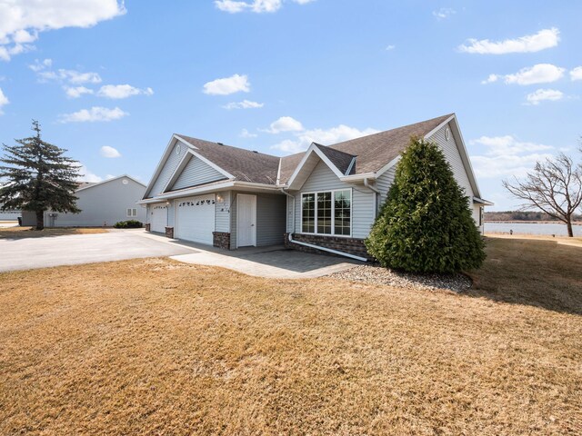view of front facade with an attached garage, driveway, roof with shingles, and a front lawn