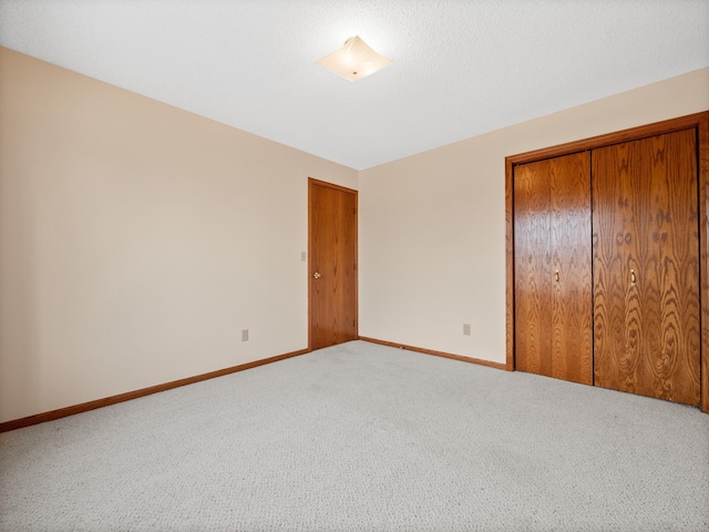 unfurnished bedroom with carpet floors, a closet, and baseboards