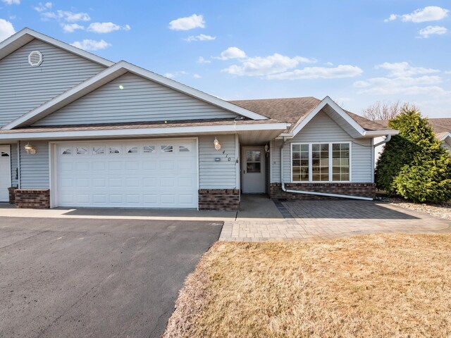 ranch-style home featuring brick siding, aphalt driveway, a shingled roof, and a garage