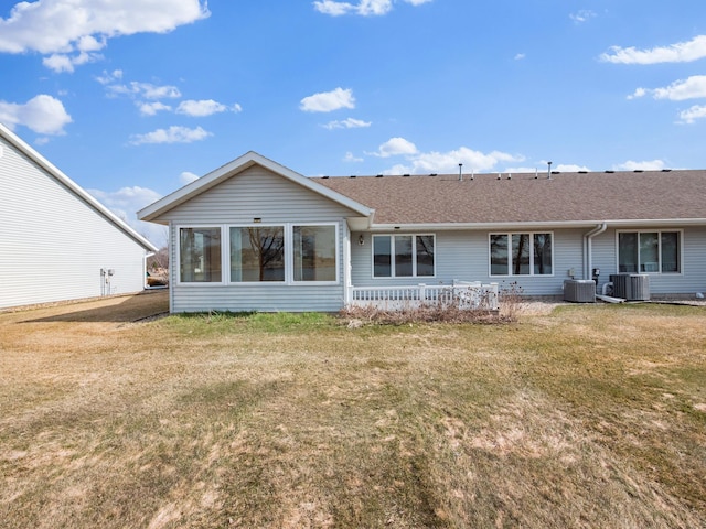 back of property with a lawn, central AC unit, and roof with shingles