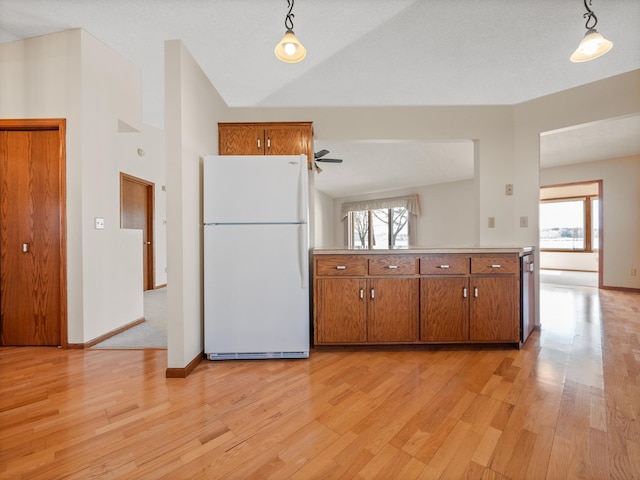 kitchen with brown cabinets, freestanding refrigerator, plenty of natural light, and light wood-style floors