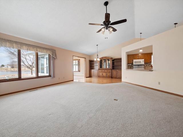 unfurnished living room featuring lofted ceiling, light carpet, baseboards, and ceiling fan with notable chandelier