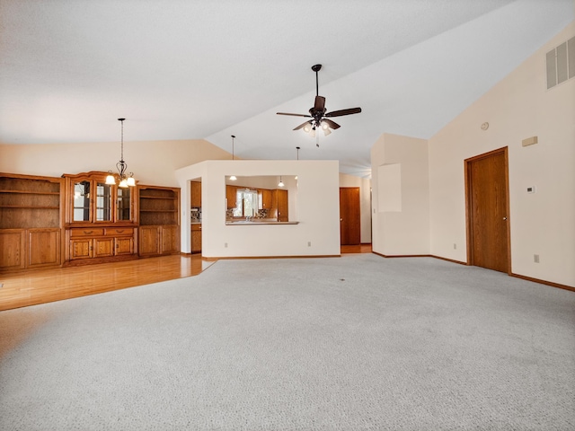 unfurnished living room featuring visible vents, light colored carpet, baseboards, high vaulted ceiling, and ceiling fan with notable chandelier