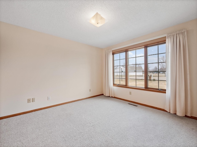 unfurnished room featuring a textured ceiling, carpet flooring, baseboards, and visible vents