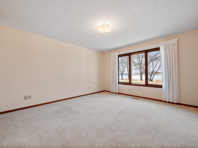 unfurnished room with a textured ceiling, baseboards, light carpet, and visible vents
