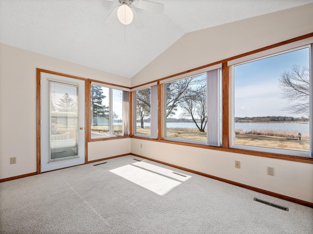carpeted spare room with a water view, visible vents, baseboards, and a healthy amount of sunlight