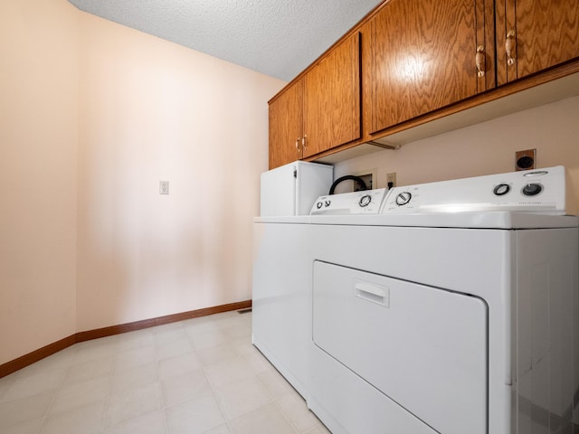 laundry room with separate washer and dryer, baseboards, a textured ceiling, and cabinet space