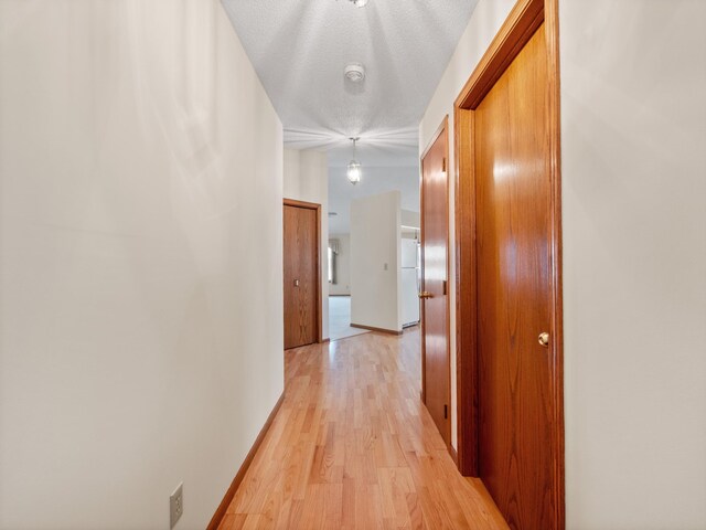 corridor featuring light wood-style flooring and baseboards