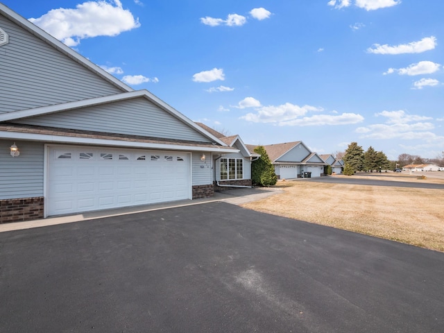 view of front of house with an attached garage, aphalt driveway, and brick siding