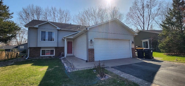 split level home with a front lawn, fence, brick siding, an attached garage, and driveway