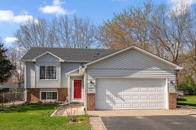 view of front of property featuring driveway, a garage, brick siding, fence, and a front lawn