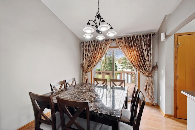 dining area featuring baseboards, an inviting chandelier, and light wood-style flooring