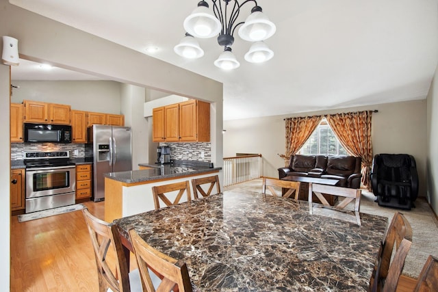 dining area featuring light wood-style floors, lofted ceiling, and a chandelier